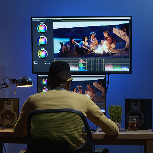 Medium shot of a young man sitting back and editing a video inside a modern video studio.